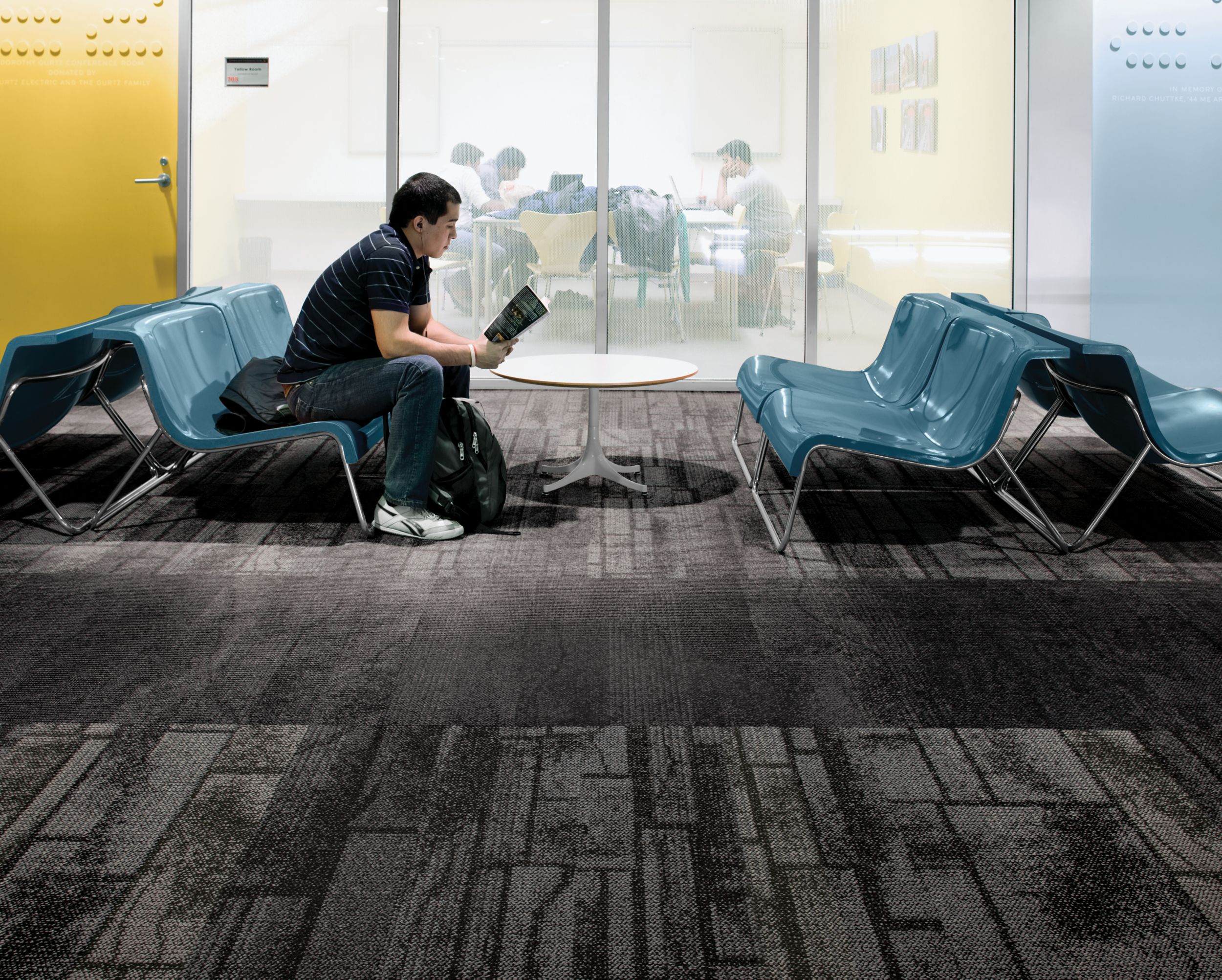 Interface Neighborhood Blocks and Neighborhood Smooth plank carpet tile in public education space with man reading a book on blue chair image number 6